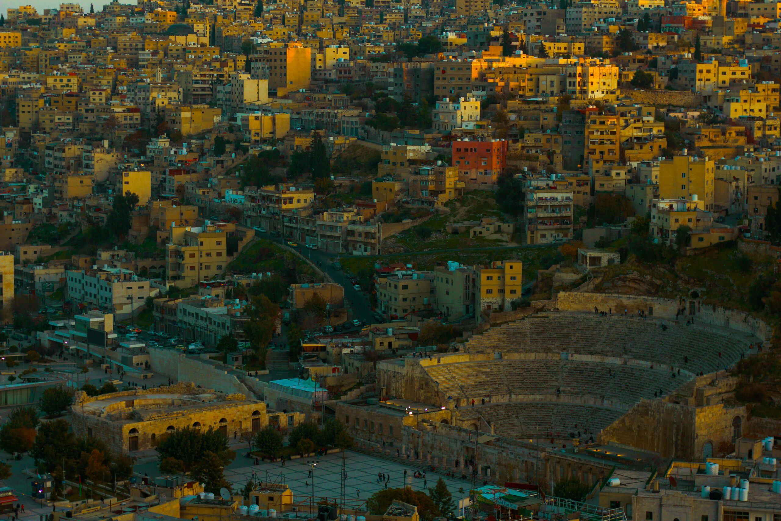 Sweeping aerial view of Amman city and iconic Roman Theatre at twilight.